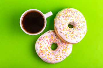 Two delicious vanilla donuts with sprinkle and cup of coffee