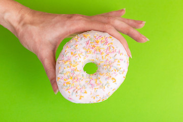 Delicious vanilla donut with sprinkle in woman's hands