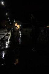 Fototapeta na wymiar couple in love embracing against a dark background, night, rain, buildings in the city, a park, smiling, attraction. the guy kisses the girl. Valentine's Day