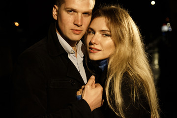 couple in love embracing against a dark background, night, rain, buildings in the city, a park, smiling, attraction. the guy kisses the girl. Valentine's Day
