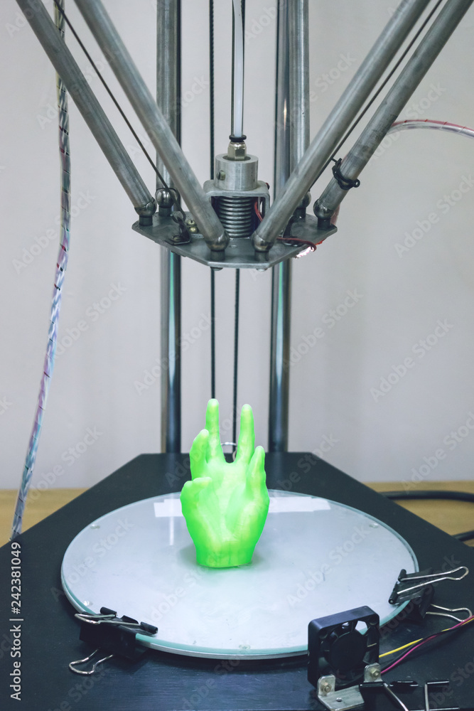 Poster green plastic 3d printed human hand stands in three-dimensional printer. object model printed on aut