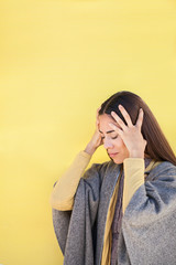 Frau mit Kopfschmerzen vor gelbem Hintergrund