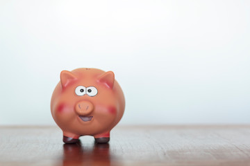Fototapeta premium Piggy bank on wooden table against white background