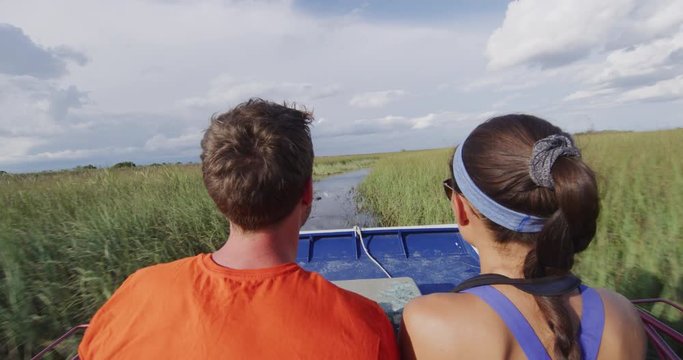 Everglades Airboat tour in Everglades in Florida - tourists couple on private air boat tour. Airboat tours are a famous tourist attraction in the Everglades. RED cinema camera in SLOW MOTION.