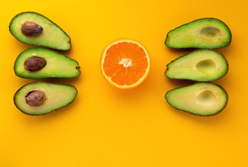 avocado and orange fruit on the yellow background with copy space