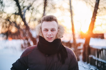 positive smiling man on a frosty morning in the snow amidst a bright winter sun.  jacket with down,...