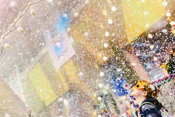 Child amazed with a rain of confetti, expression of amazement and happiness.