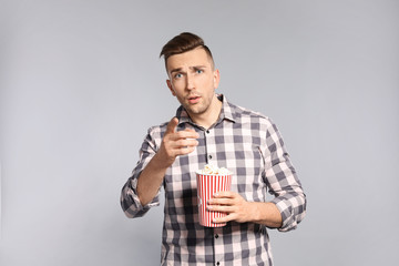 Emotional man with popcorn during cinema show on grey background