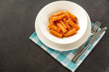Penne Amatriciana fresh pasta with parmesan cheese on dark backg