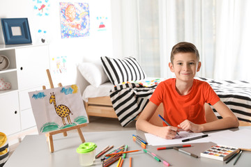 Little child drawing picture at table with painting tools indoors