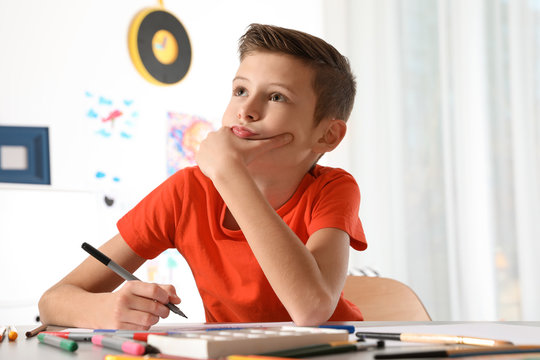 Little child drawing picture at table with painting tools indoors