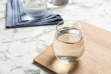 Wooden board with glass of fresh water on marble table. Space for text