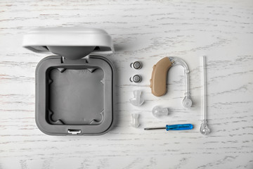 Flat lay composition with hearing aid and accessories on white wooden background