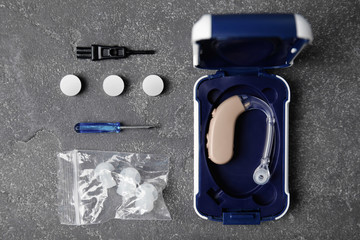Flat lay composition with hearing aid and accessories on grey background