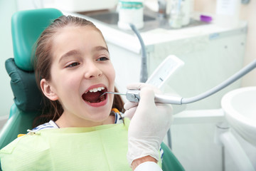 Professional dentist working with little patient in modern clinic