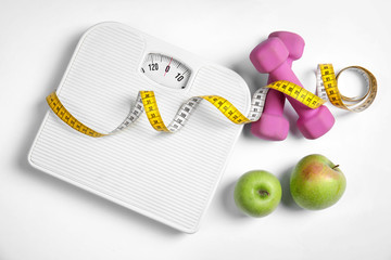 Composition with scales, apples, tape measure and dumbbells on white background, top view