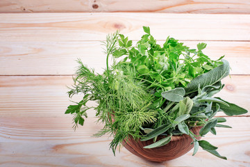 Fresh herb leaves variety in wood bowl on table