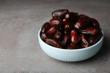 Bowl with sweet dates on grey background, space for text. Dried fruit as healthy snack
