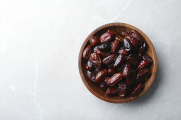 Bowl of sweet dates on grey background, top view with space for text. Dried fruit as healthy snack