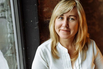 Close-up portrait of a beautiful woman in white shirt near the window. Business woman