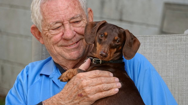 Happy, smiling senior man holding his dog