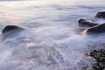 Dreamy surf flowing over rocky shore