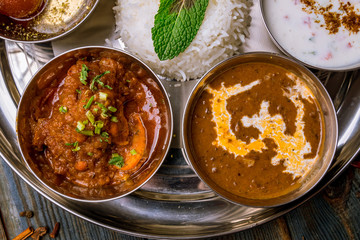 Assorted indian food set on wooden background. Dishes and appetisers of indeed cuisine, rice, lentils, paneer, samosa, spices, masala. Bowls and plates with indian food