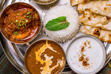 Assorted indian food set on wooden background. Dishes and appetisers of indeed cuisine, rice, lentils, paneer, samosa, spices, masala. Bowls and plates with indian food