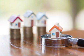Miniature of house with magnifying glass and coin,  choice of location for the construction, of...