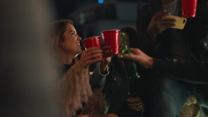group of multiracial friends celebrating birthday party on rooftop at night drinking alcohol making toast to friendship having fun sharing celebration