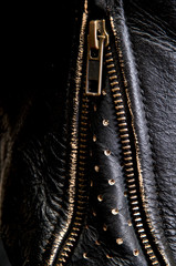 Detail of old distressed leather motorcycle jacket focusing on open wrist zipper.