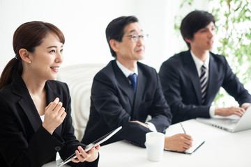 三人のビジネスチームが前を向き明るい表情を浮かべているシーン