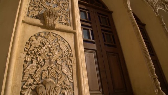 Handheld, close up, exterior, low angle shot panning down a wall of The Borujerdi House Garden in Kashan.