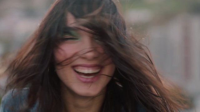 close up portrait happy asian woman on rooftop shaking hair blowing in wind enjoying freedom laughing cheerfully in urban city