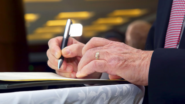 the hand of a business man signs an important document with a pen