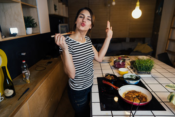 Young woman cooking a healthy meal in home kitchen.Making dinner on kitchen island standing by...