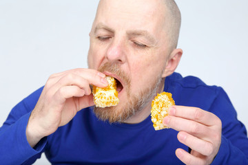 bearded man in a blue sweater eating a honeycomb