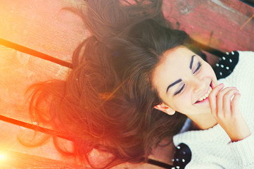 Beautiful girl with gorgeous hair lying on the boards with his eyes closed and smiling, topic view closeup