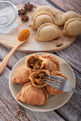 Fototapeta premium Traditional curry puffs stuffed chicken with raw curry puffs on wooden table as background