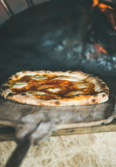 Freshly baked pizza with cheese in pizza wood oven, selective focus, vertical composition