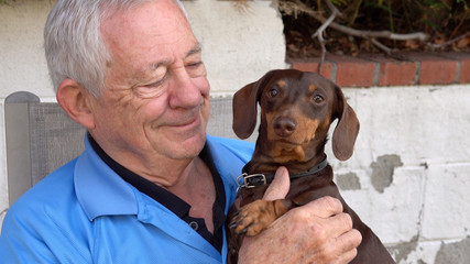 Handsome senior man holding his puppy - Powered by Adobe