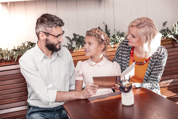 Nice pleasant family reading the menu together