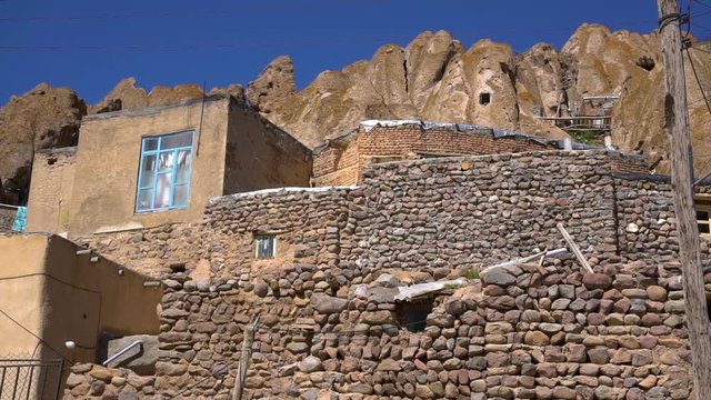Steady, wide, exterior, daytime shot of homes and stone walls in the Kandovan Village.
