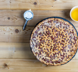 cake with berries and rhubarb and cup of tea on a wooden table.