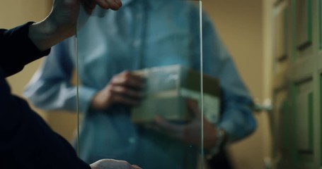 Woman signing on futuristic augmented reality delivery device a parcel from mailman  delivered in her home. Shot with RED camera i 8K. Concept of courier, delivery, e-commerce, online shopping