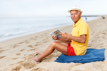 Nice mature man  sitting and looking at booklet