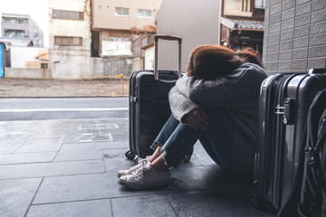 A woman sitting with feeling sad while traveling with a lot of baggages on the floor