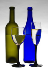 Glass of wine and bottles on light gray