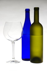 Glass of wine and bottles on light gray