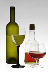 Glass of wine and bottles on light gray